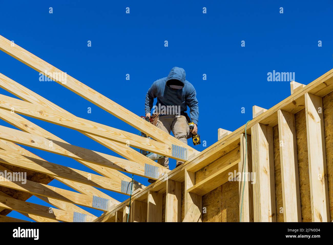 Aerial view of a builder on the unfinished roof with nailing wooden