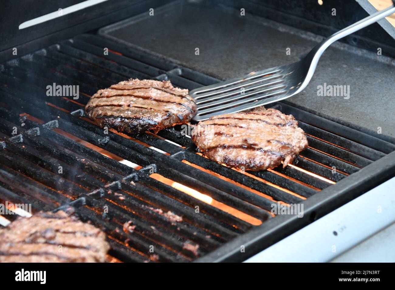 Flamed grilled beef burgers barbecued on an outdoor BBQ Stock Photo
