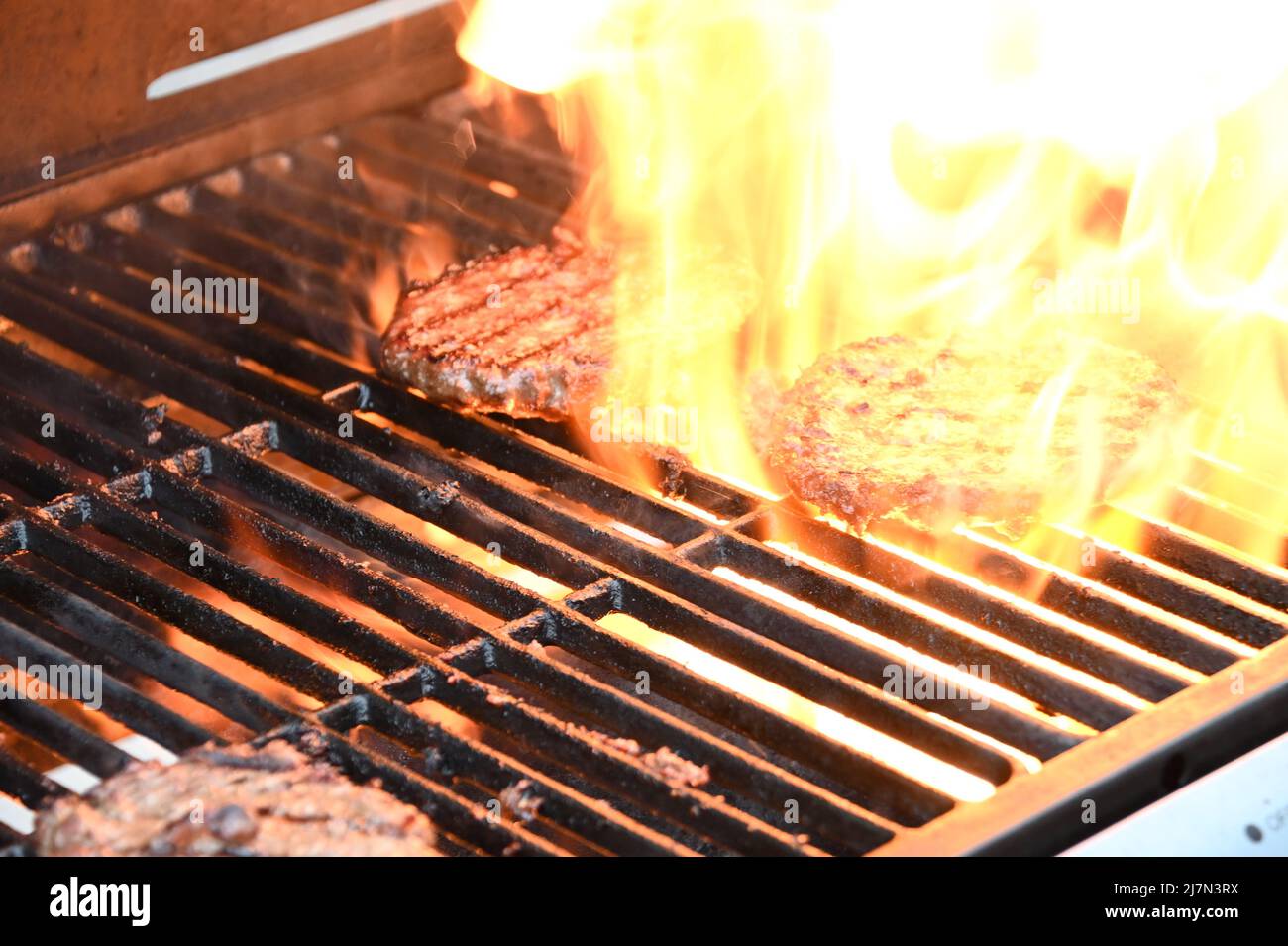 Flamed grilled beef burgers barbecued on an outdoor BBQ Stock Photo