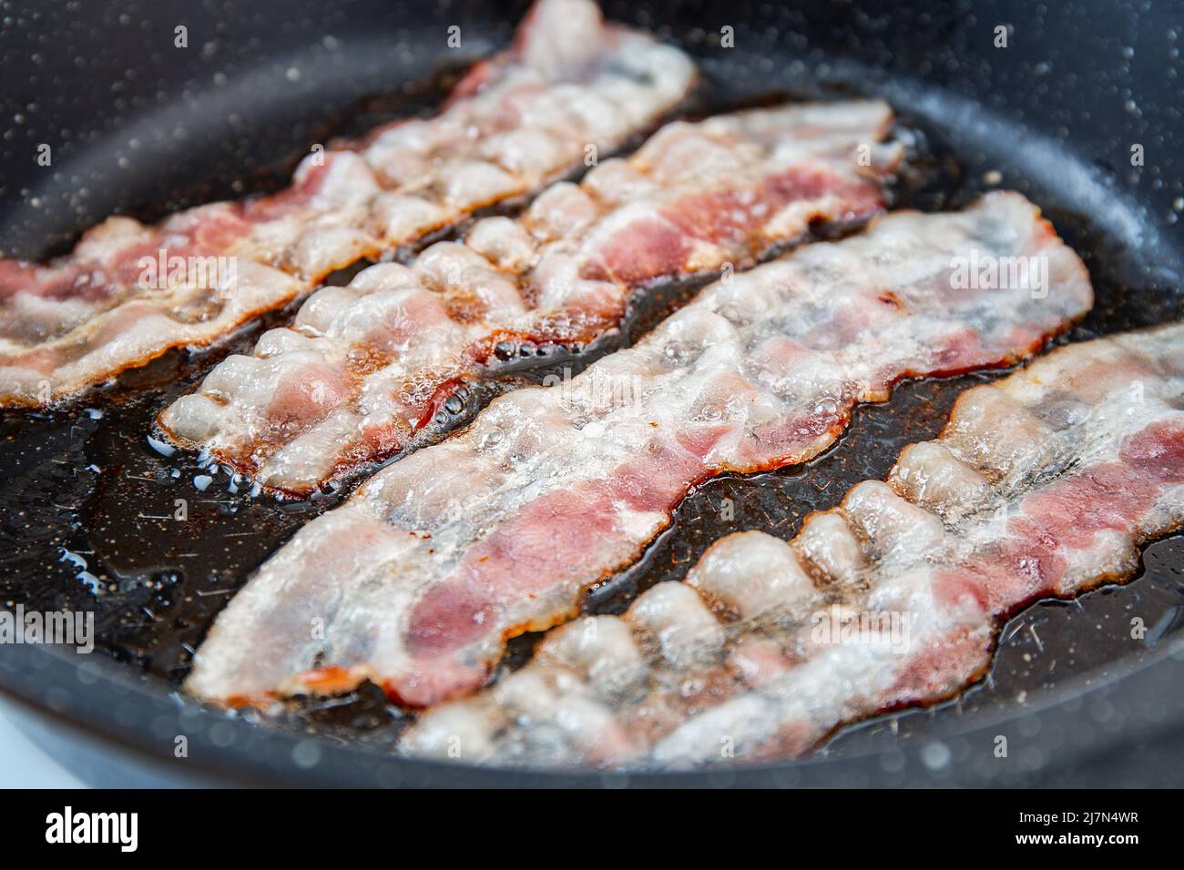 Crispy smokey fried bacon slice or strip. Unhealthy fat food, fattenig