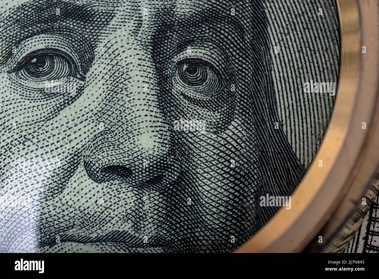 Close-up portrait of Ben Franklin on the US 100 dollar bill under a magnifying glass. Benjamin Franklin on one hundred dollar American banknote, close Stock Photo