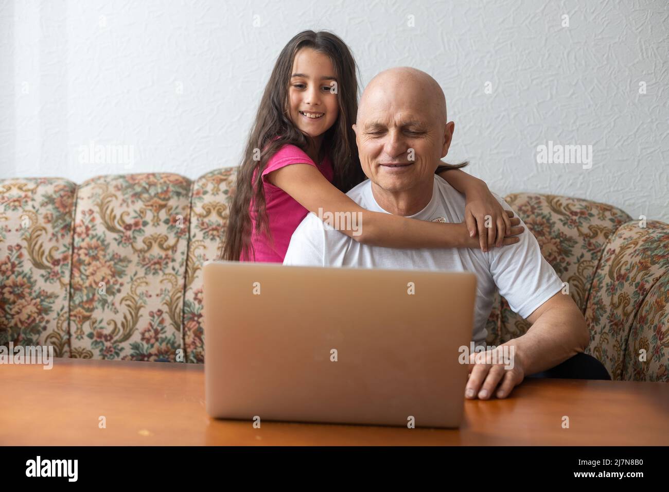 Grandfather and granddaughter spend time together use laptop, browse