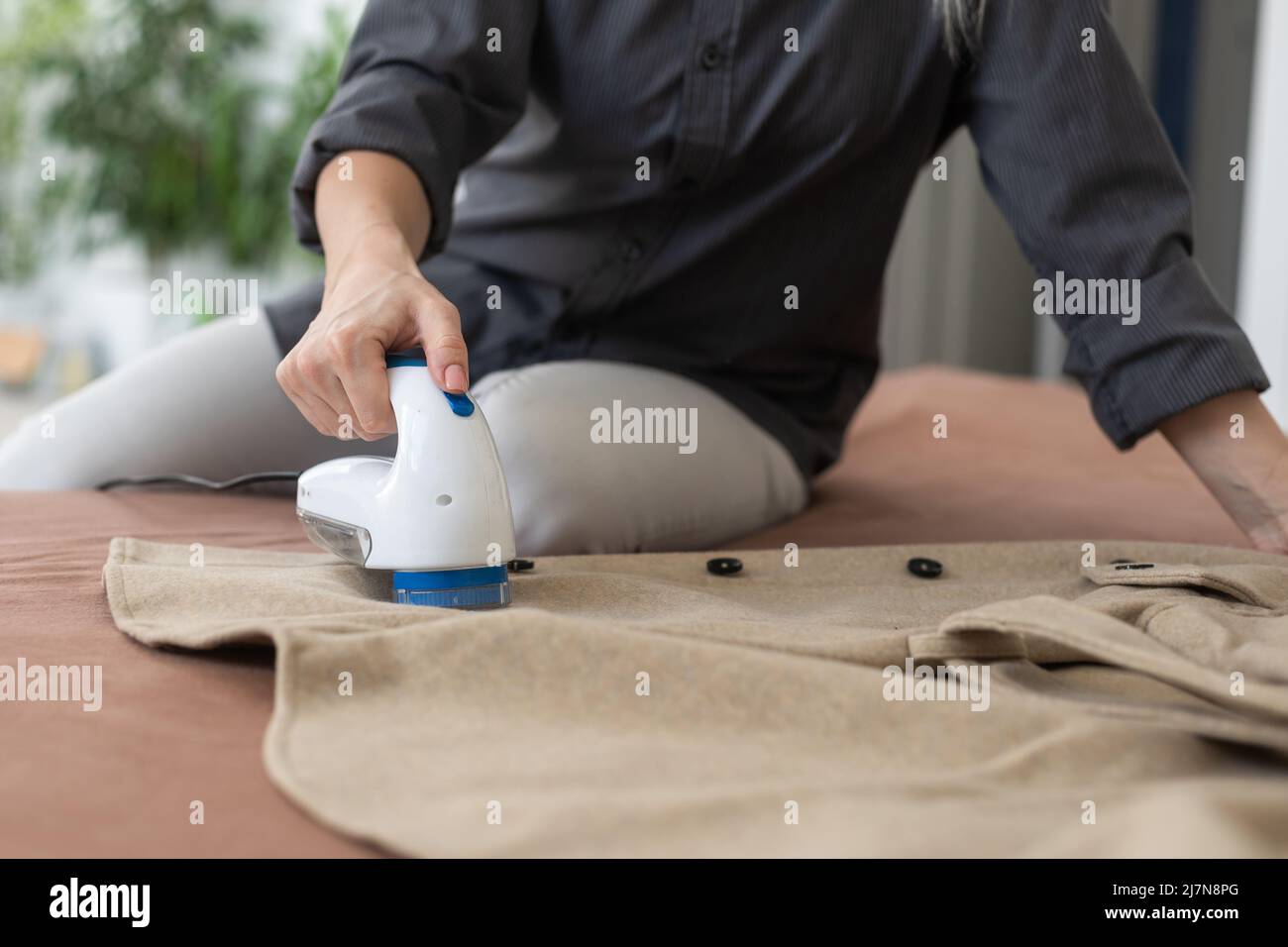 Wireless device for cleaning knitted fabrics from lint. The woman is