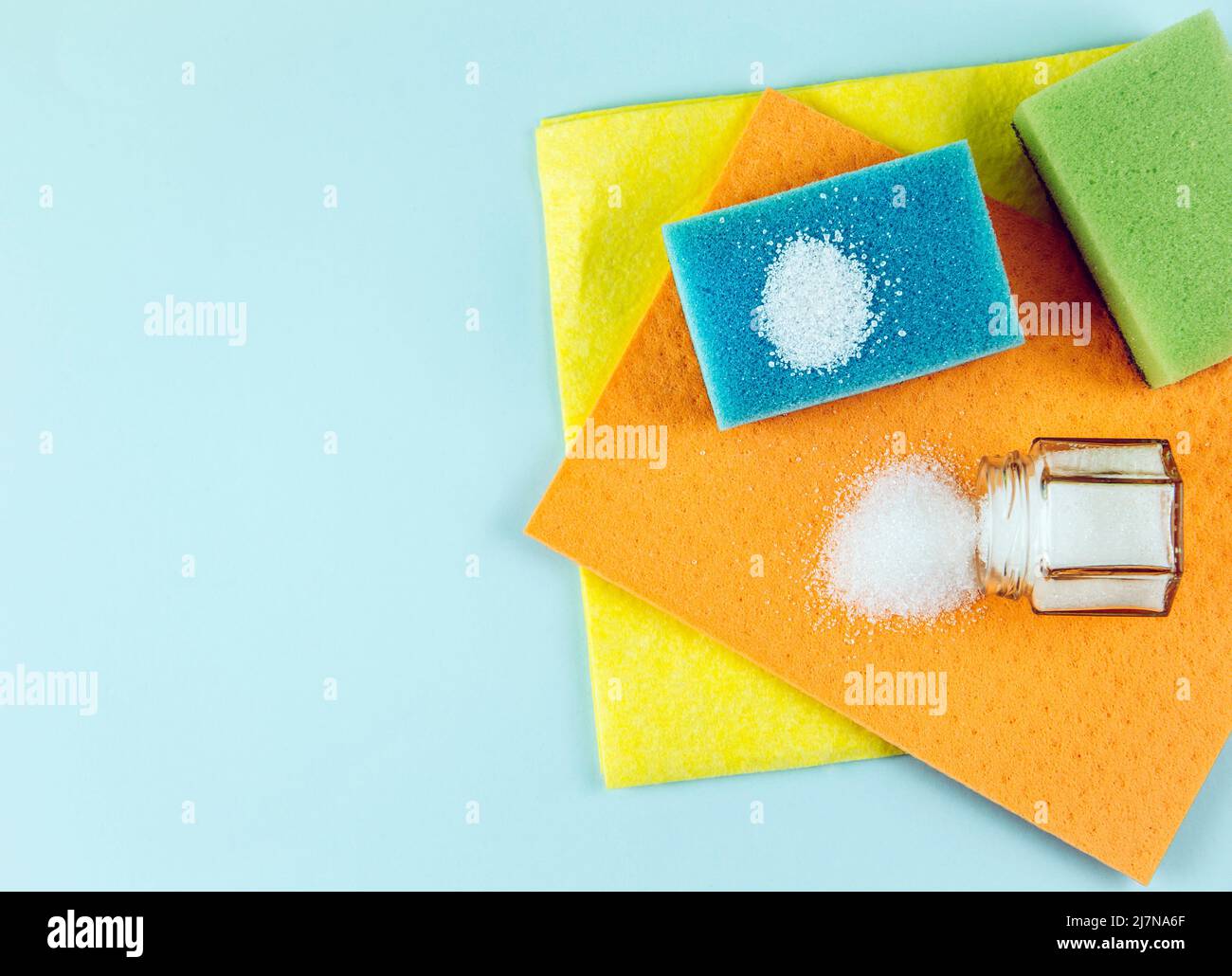 Natural organic citric acid cleaning products concept. White Citric acid powder on blue washing sponge and in jar. Lot of copy space on blue. Stock Photo
