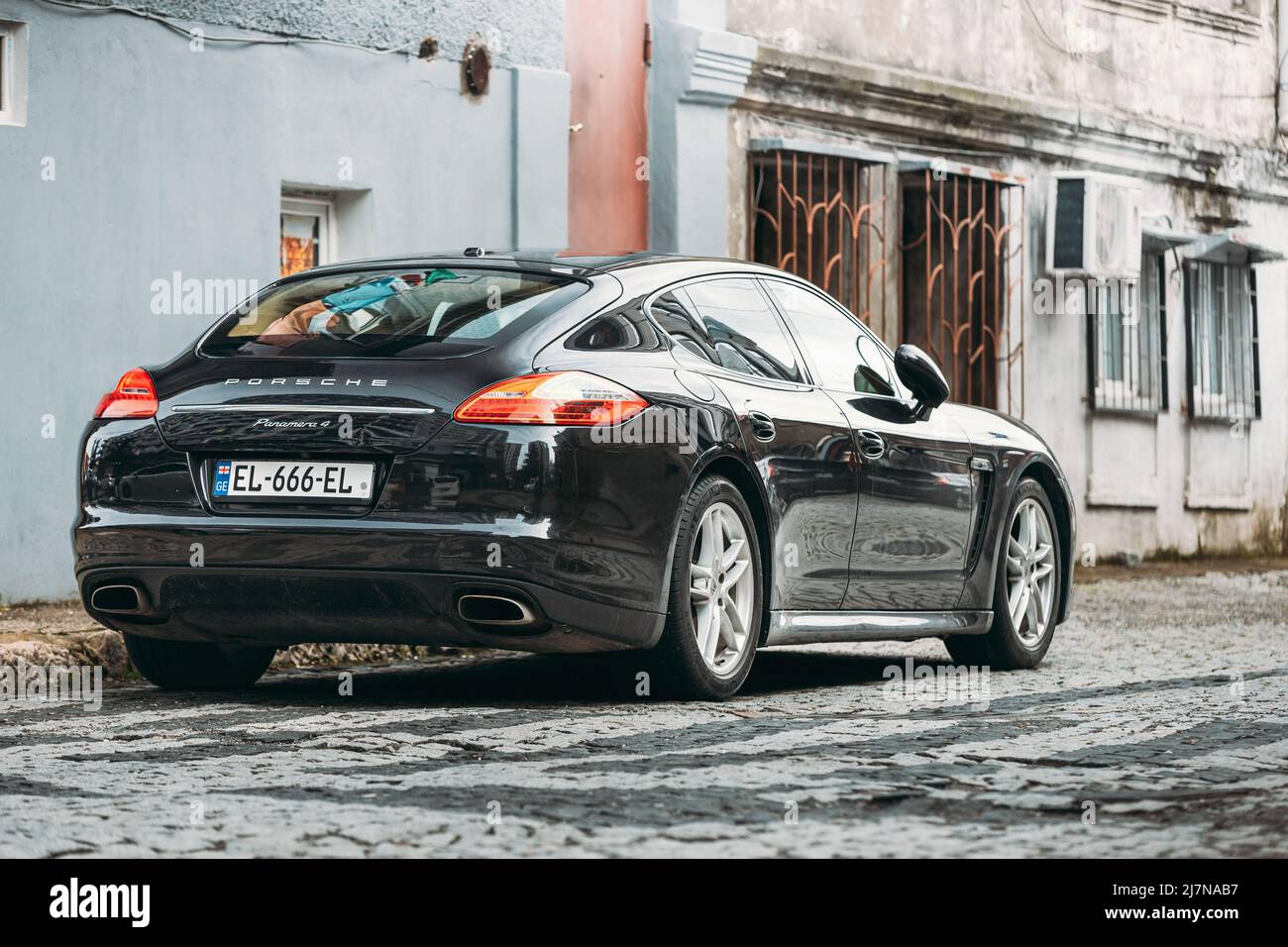 Black porsche panamera 4 Parking In City Street with old buildings. Stock Photo