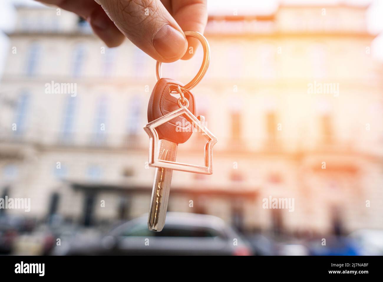 Keychain in the shape of a house with a key in the hands of a person against the backdrop of an expensive fashion house Stock Photo