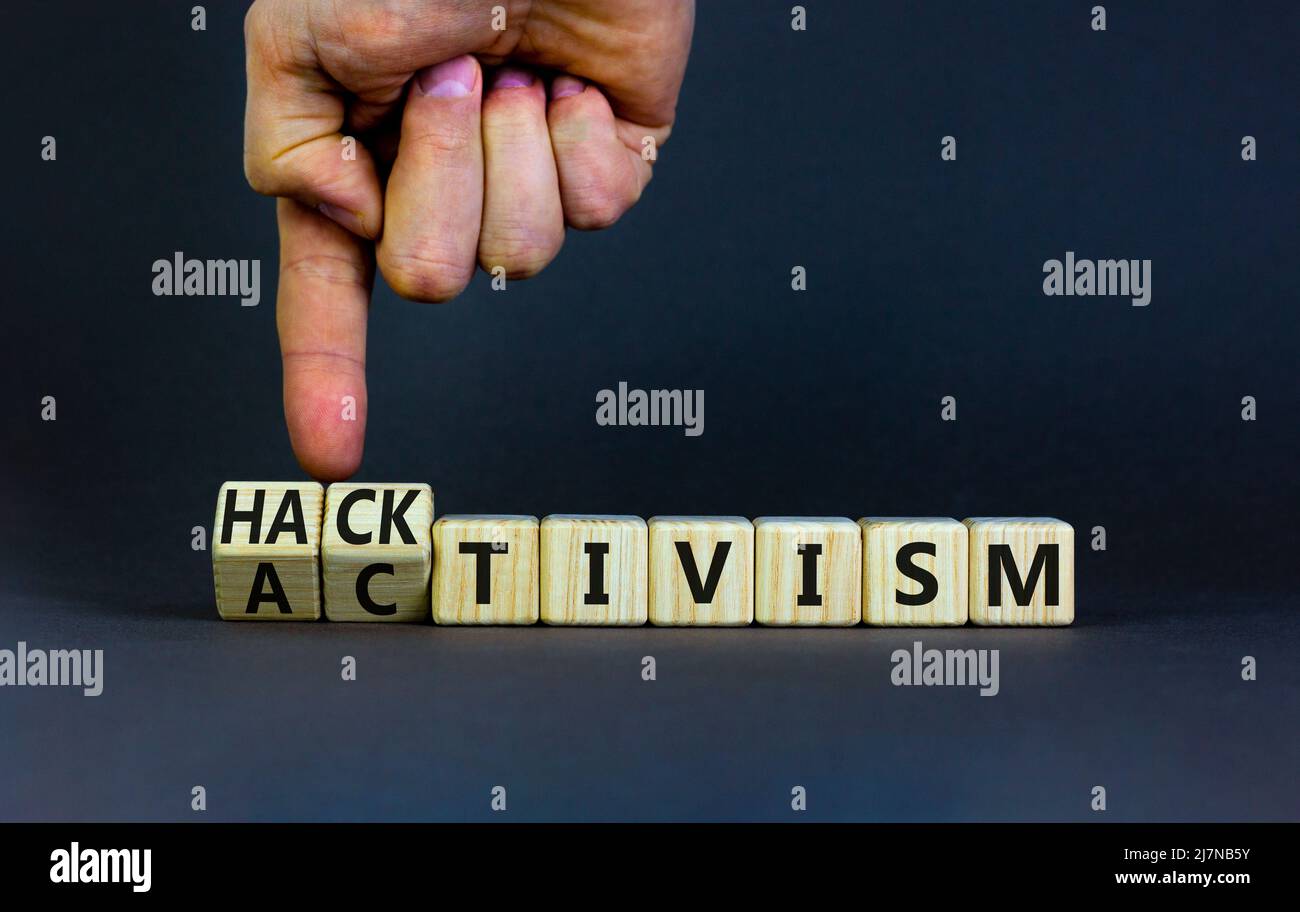Activism or hacktivism symbol. Businessman turns wooden cubes and changes the word Activism to Hacktivism. Beautiful grey table grey background, copy Stock Photo