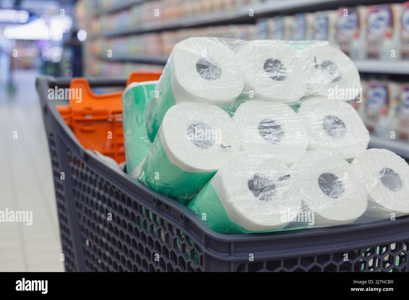 Shopping trolley full of toilet paper packs in supermarket Stock Photo