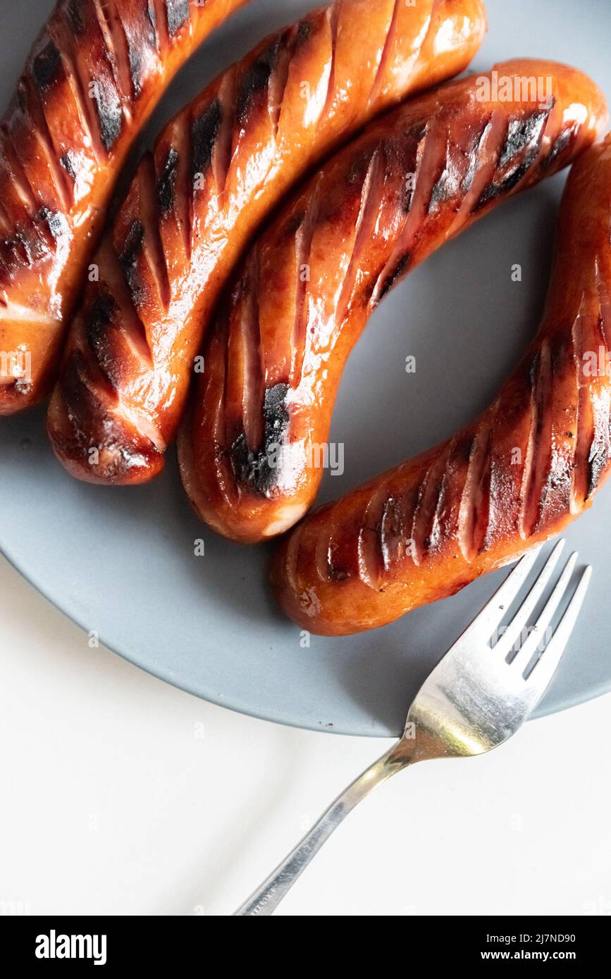Grilled sausage on a plate, next to a fork. Grilled dish, sausage Stock Photo Alamy
