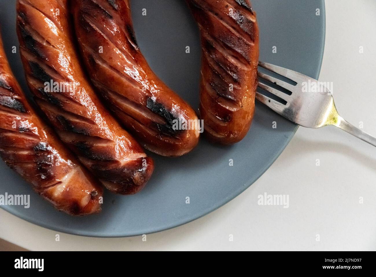 Grilled sausage on a plate, next to a fork. Grilled dish, sausage Stock Photo Alamy