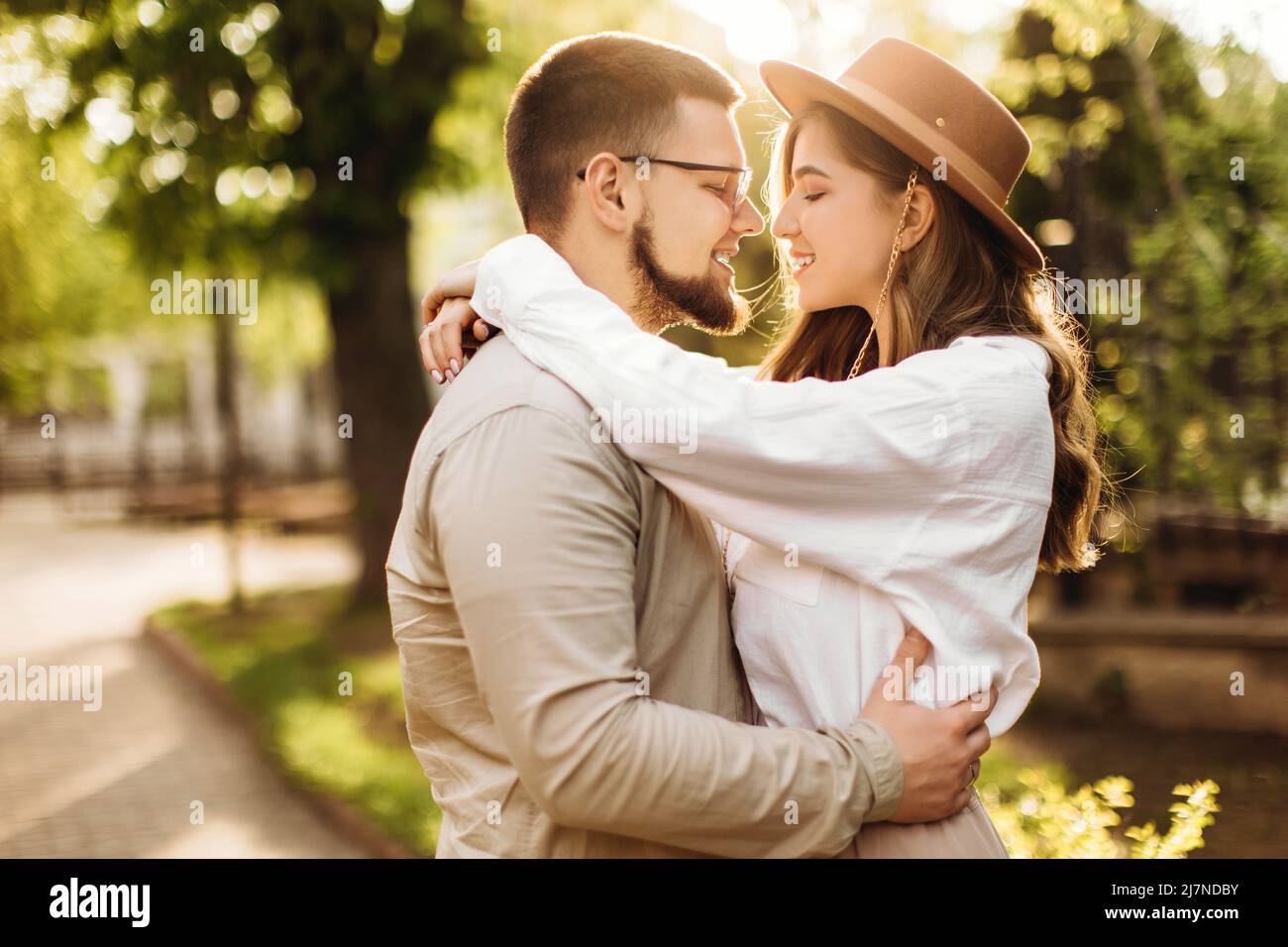 Lovely happy couple smiling and hugging in the sun. A beautiful girl ...