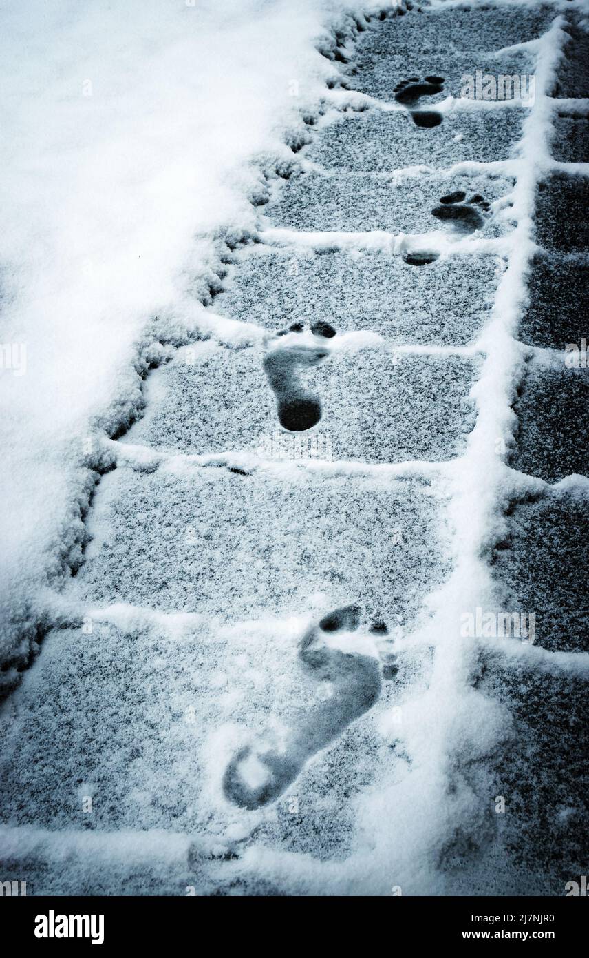 seasonal background footprints feet on the snowy sidewalk Stock Photo
