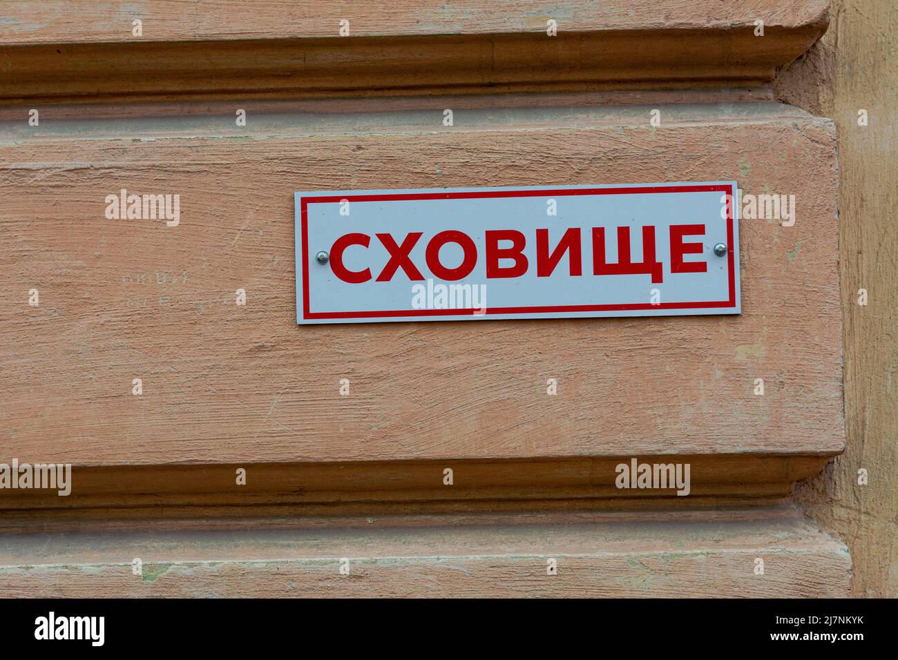 A plate on the wall of a house with the inscription SHELTER in a Ukrainian city. The war between Russia and Ukraine, grief, a sign of a bomb shelter f Stock Photo