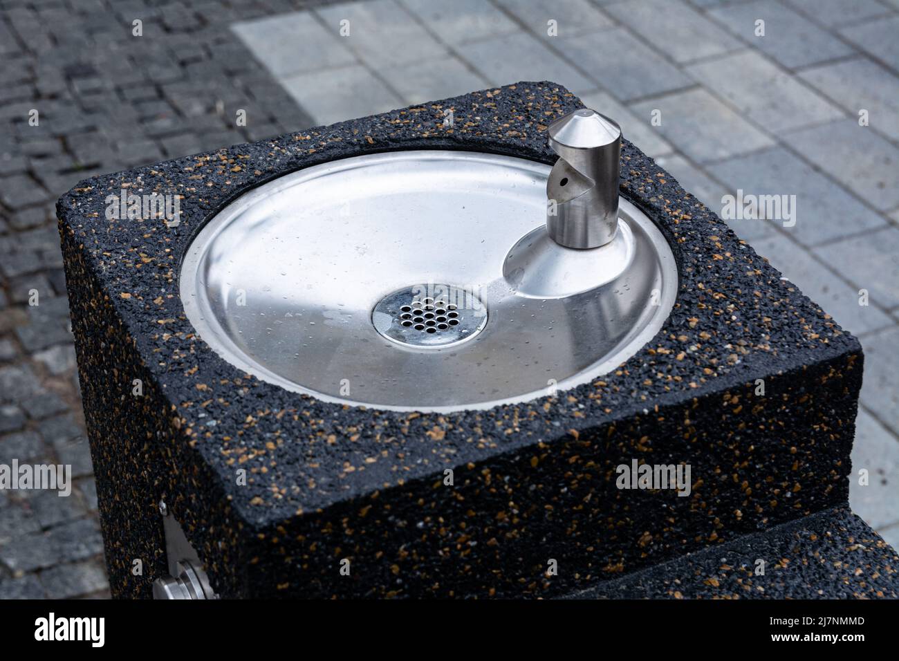 Urban drinking fountain with stone base, chromed stainless steel sink