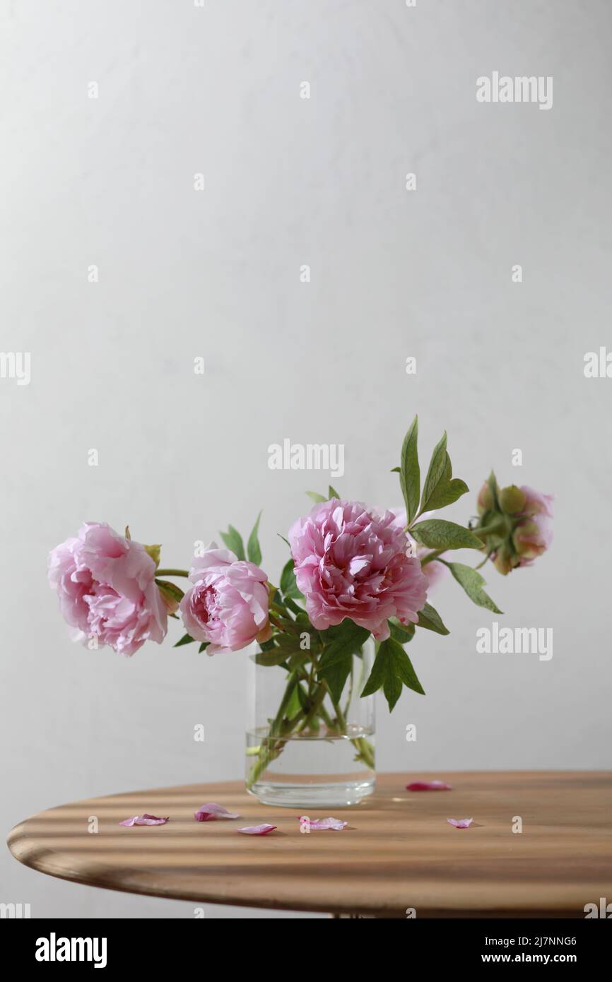 Pastel pink peony flowers bouquet in a glass vase on wooden table Stock ...