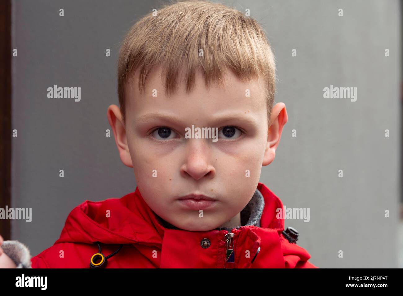 The serious boy. Serious Face of a boy in a red jacket. Portrait of a caucasian boy. Stock Photo