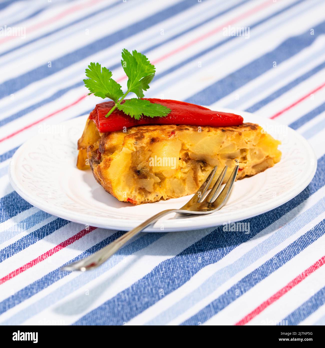 Traditional Spanish starter tortilla patatas served with red piquillo pepper. Stock Photo