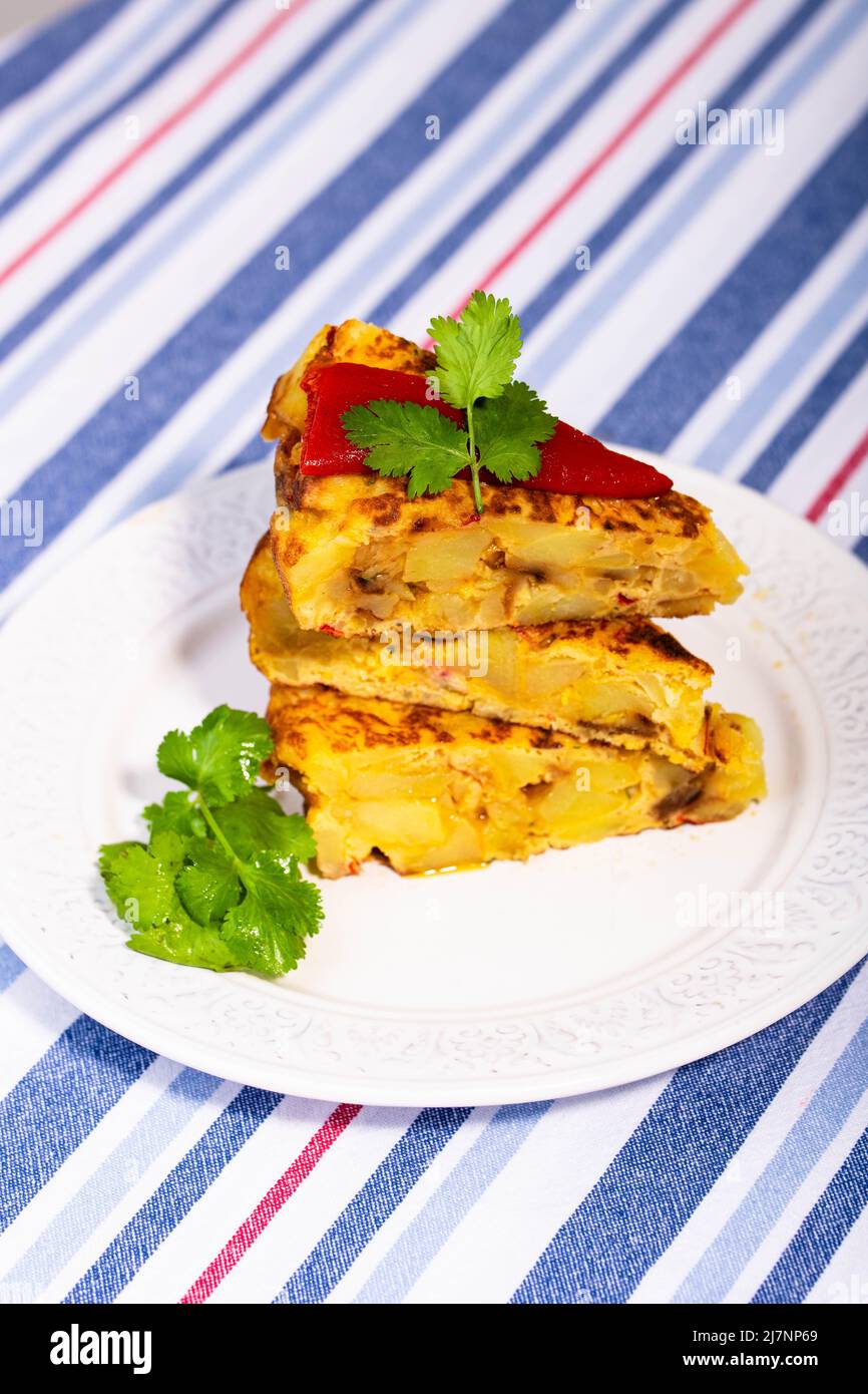Traditional Spanish starter tortilla patatas served with red piquillo pepper. Stock Photo