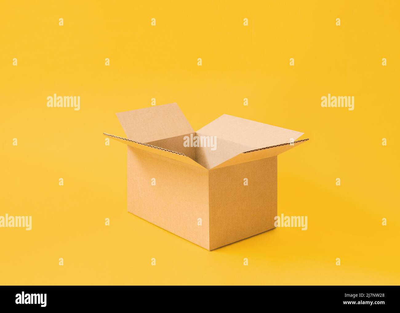 Opened cardboard box on bright yellow background Stock Photo
