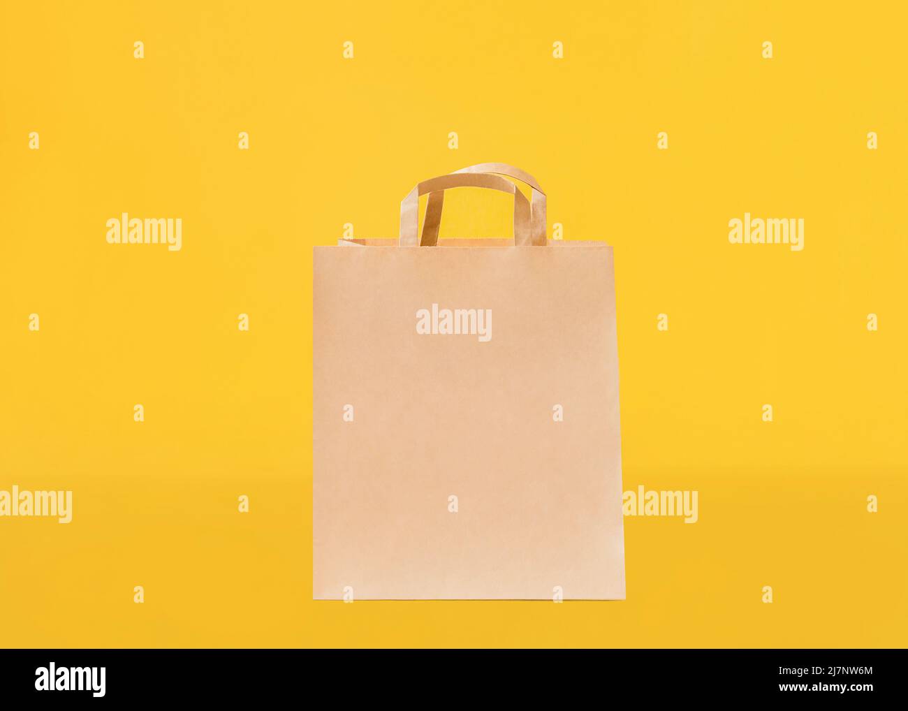 Kraft bag with handles on yellow backdrop Stock Photo