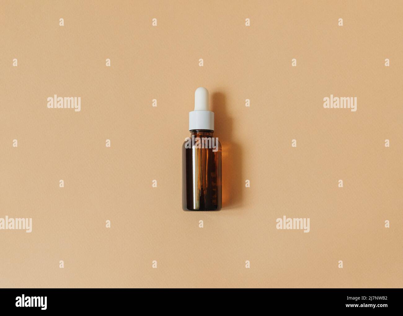 Liquid cosmetic in brown glass bottle on beige backdrop Stock Photo
