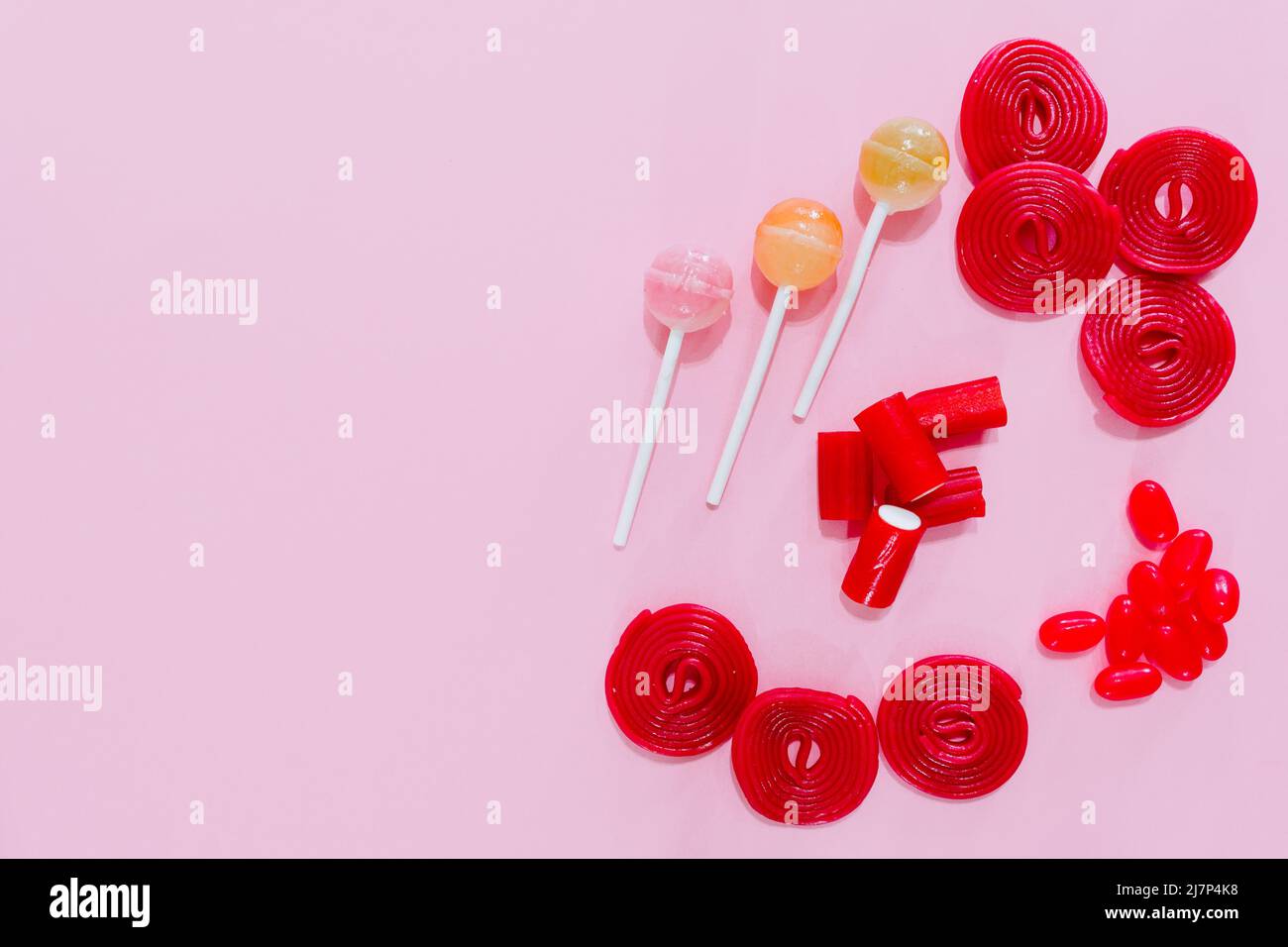 candies and red lollipops on a plain pink background. wallpaper to use text. graphic resource. Stock Photo