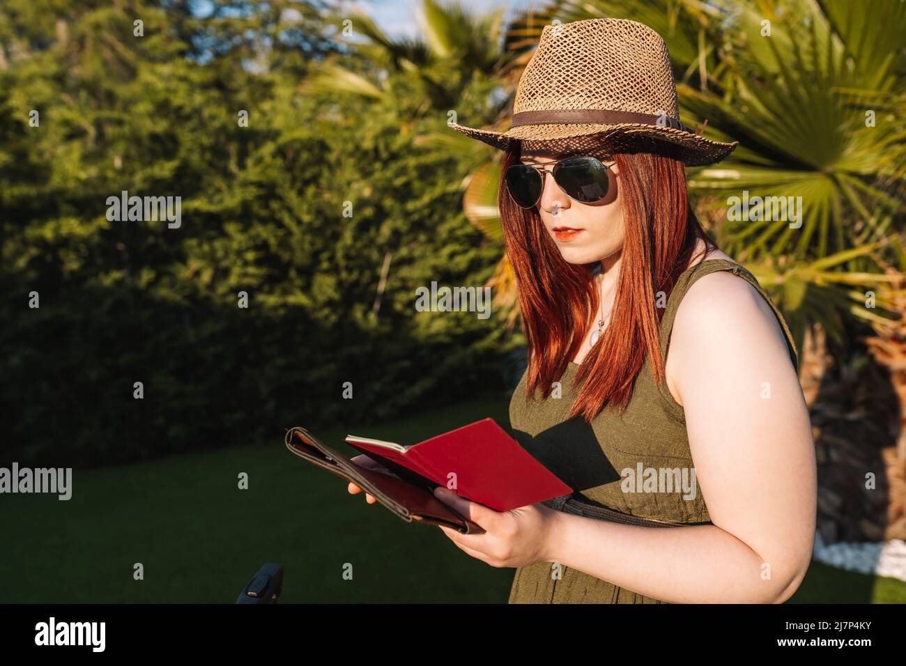 young woman on summer holiday, checking her passport at a tropical resort. Concept of trip, holiday, relaxation, hotel. Stock Photo