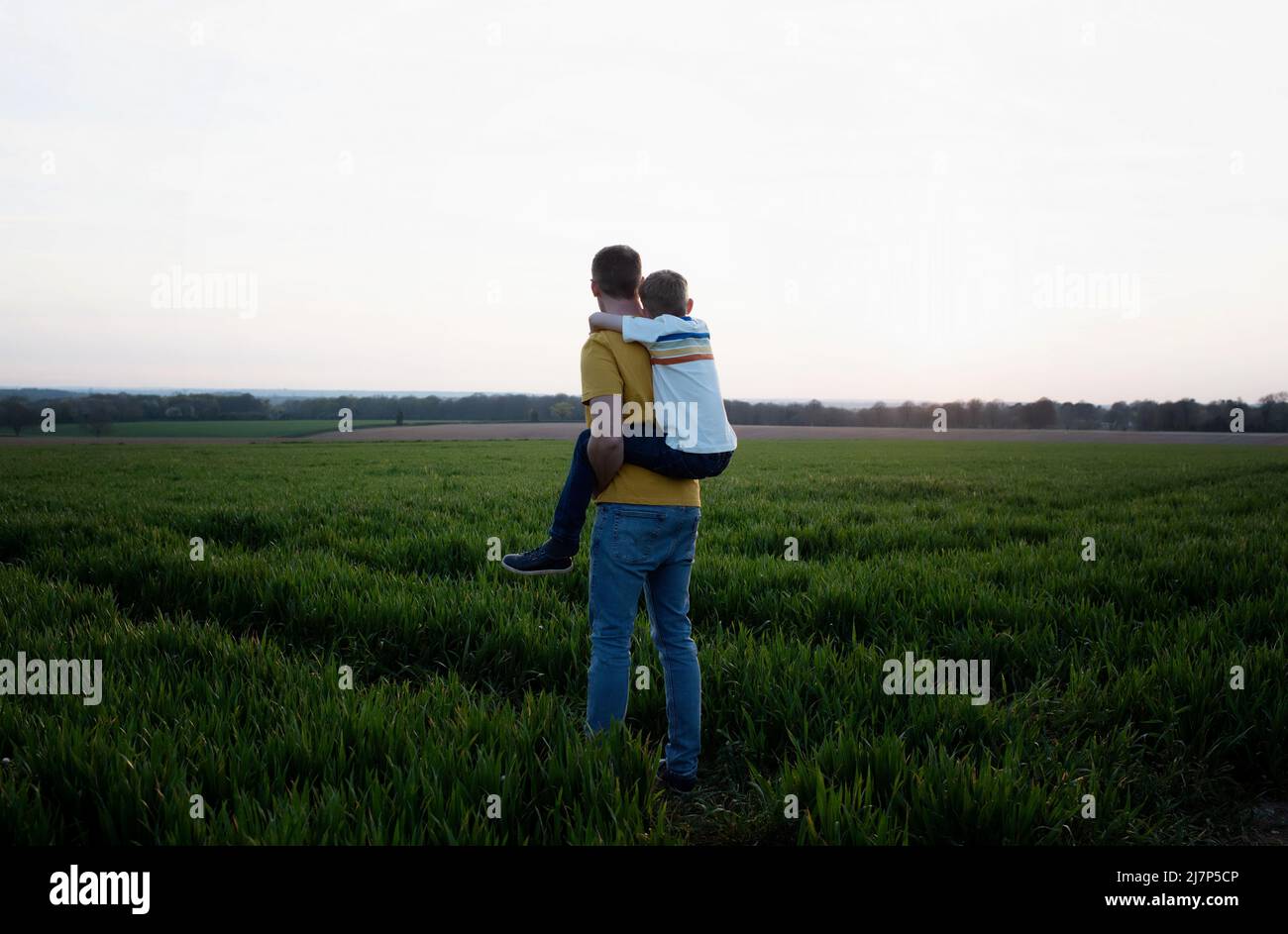 father giving his son a piggyback whilst walking in the countryside Stock Photo