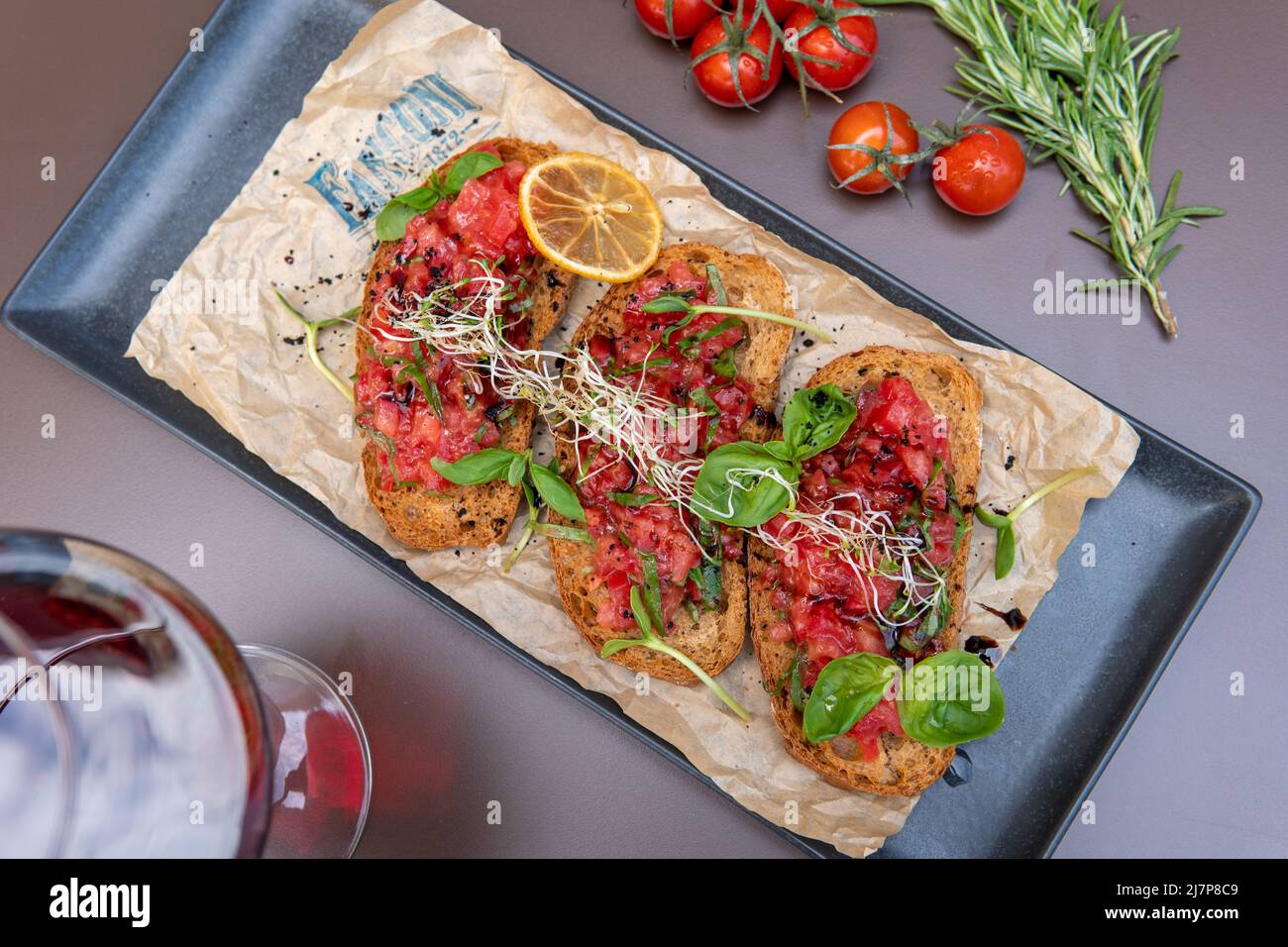a bruschetta with tomatoes on a dark table, a glass of red wine Stock
