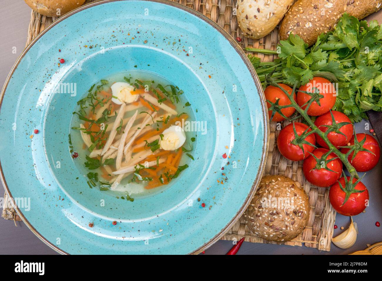 Chicken broth with homemade pasta, carrots, fillets and quail eggs Stock Photo