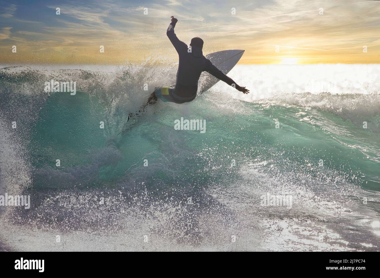 Energetic, unidentifiable surfer at sunset. Stock Photo