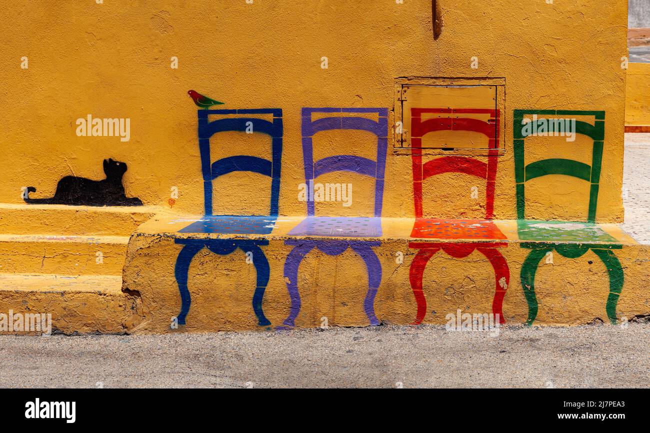 Famous Illustration on Linosa's wall of a cat looking at a bird sitting on a chair, Pelagie island. Sicily Stock Photo