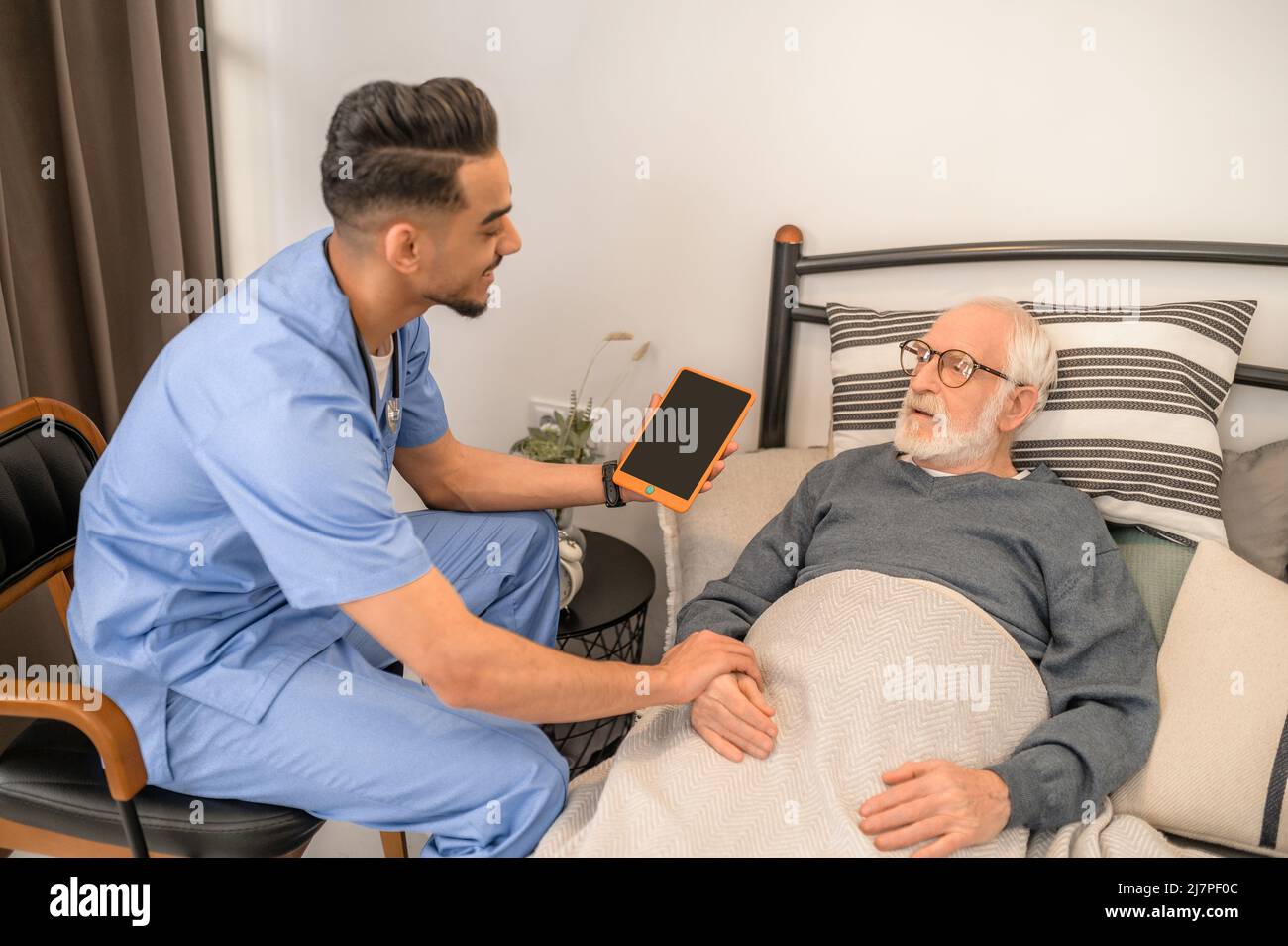 General practitioner examining a bedridden man during the home visit