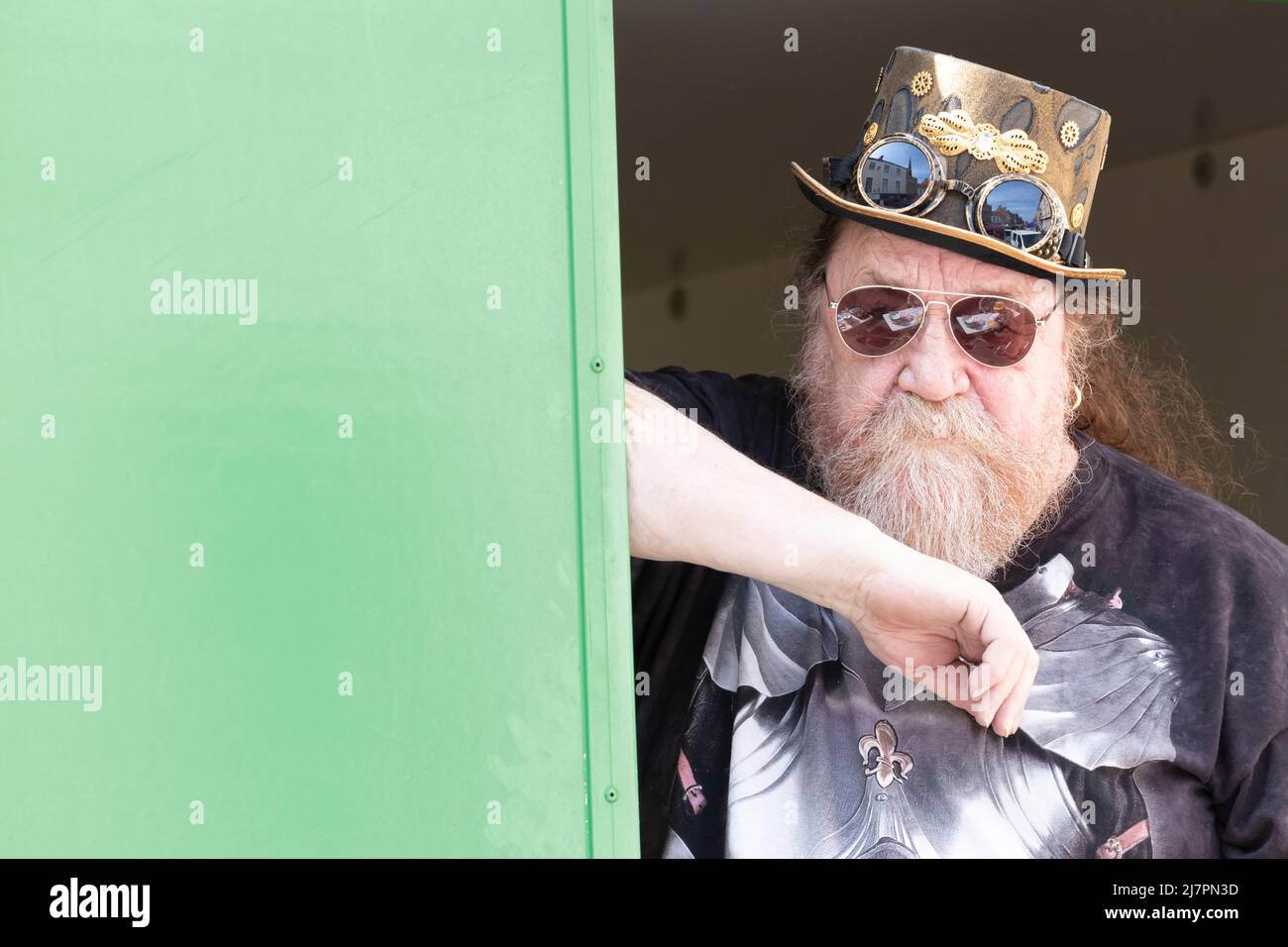 Bearded steampunk top hat man in sunglasses with a serious surly look on his face at street fair Stock Photo