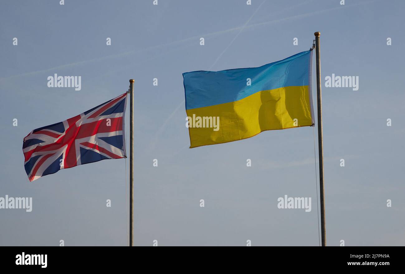 UK and Ukrainian flags seen flying side by side on flagpoles side by side in the UK. Stock Photo