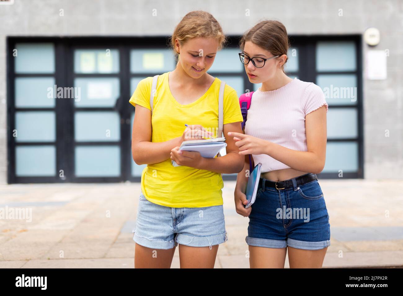 Two happy female students walking and talking each other in campus Stock Photo