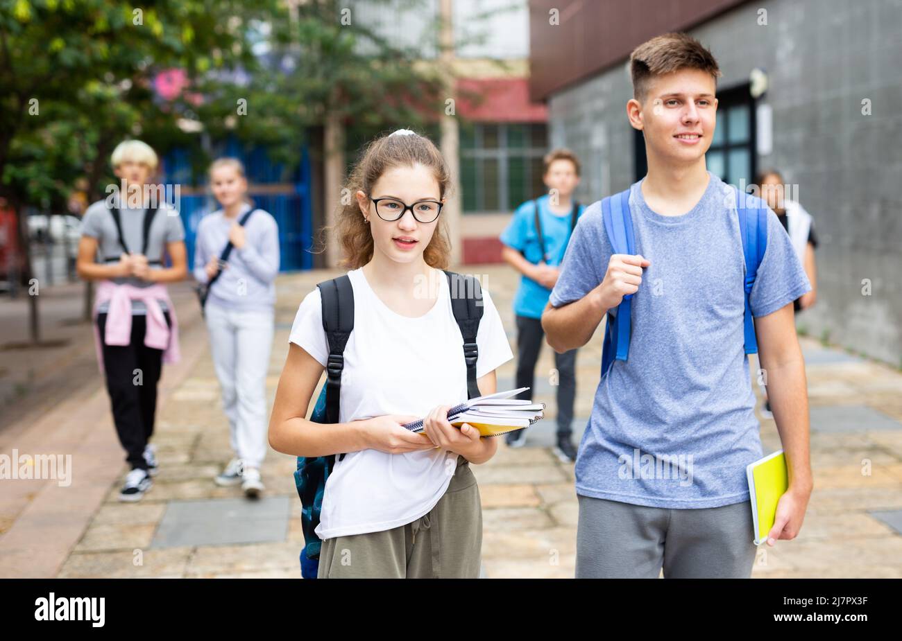Students with backpacks and notebooks walk down the street Stock Photo ...
