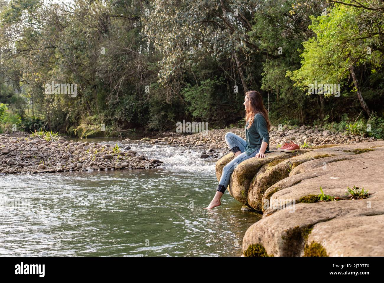 Woman sitting on a rock and relaxing in nature Stock Photo - Alamy