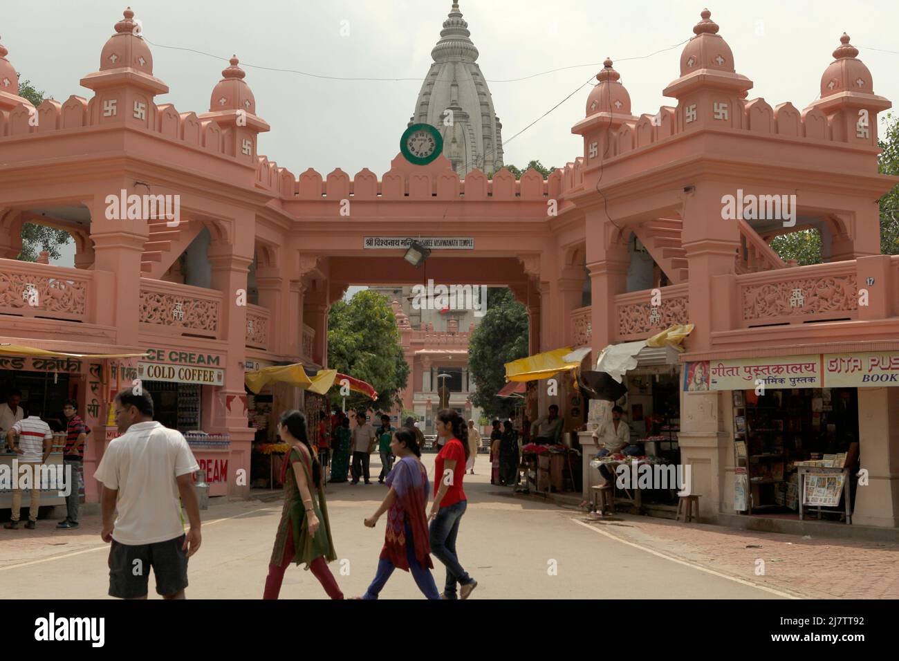 People walking on a street pinched by shops leading to Viswanath temple 