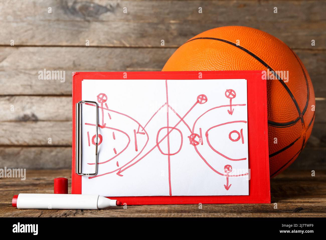 Clipboard with drawn scheme of basketball game and marker on dark