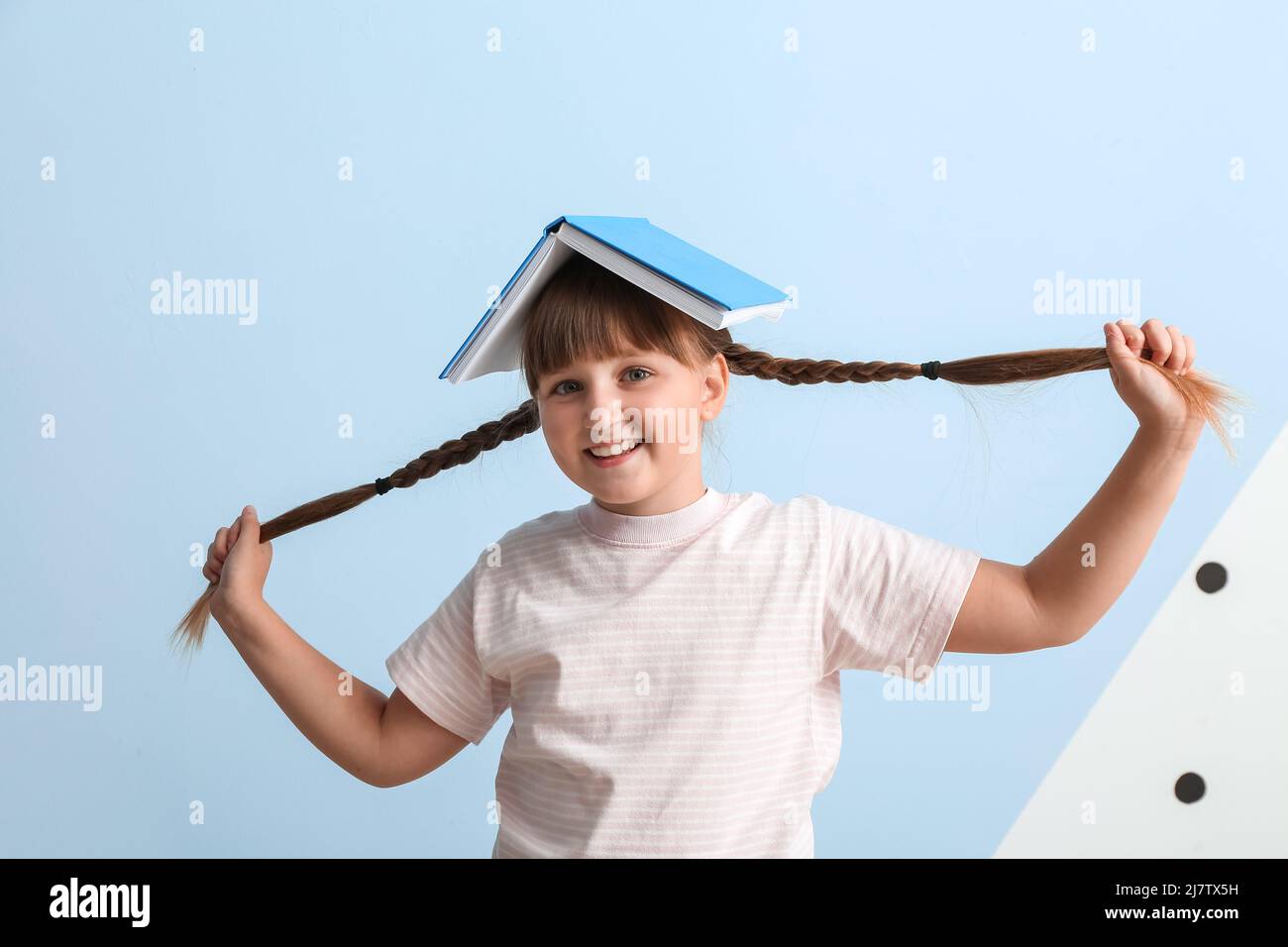 Little girl with braids and book on blue background Stock Photo - Alamy