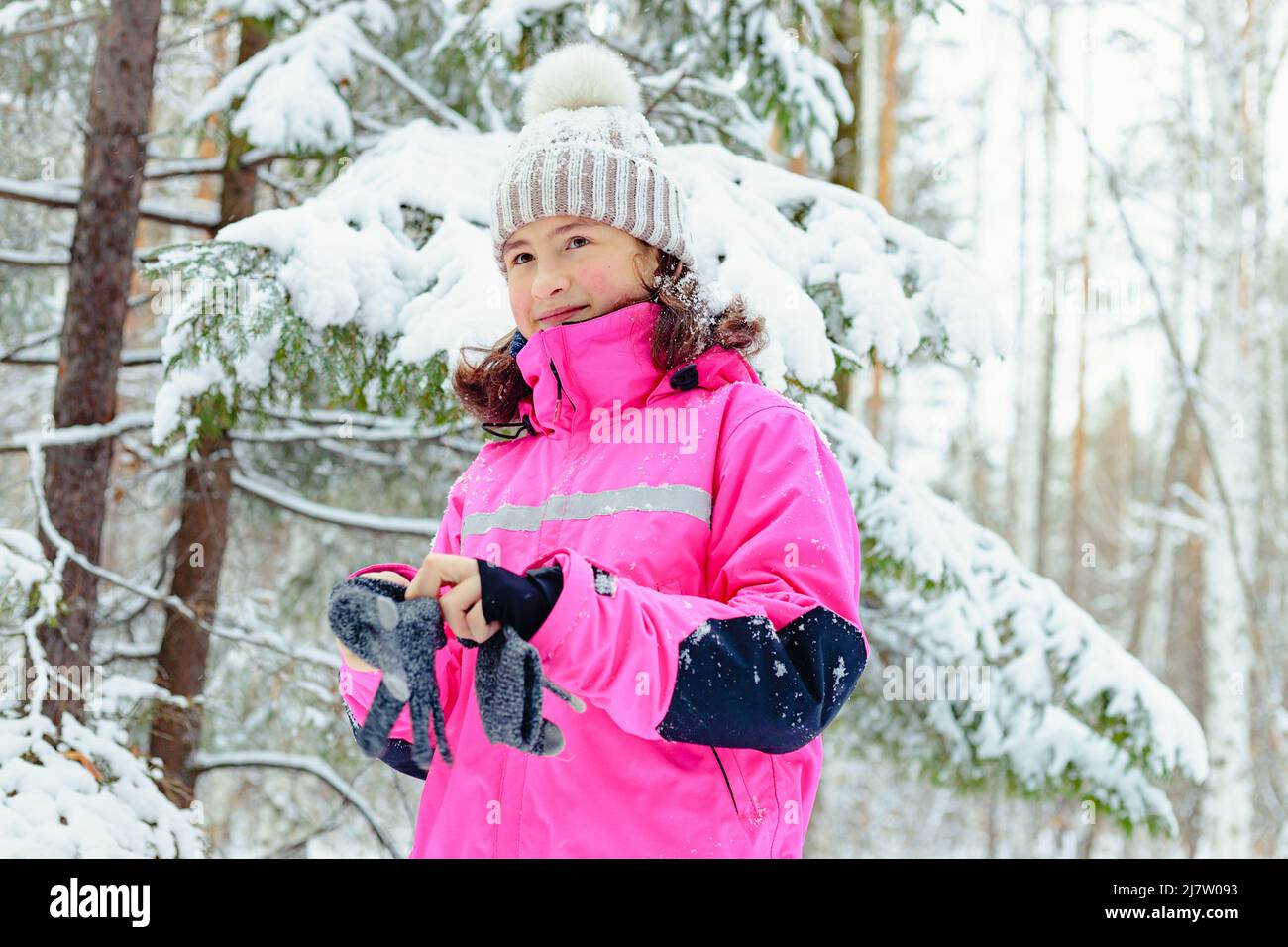 Portrait of a teenager girl in bright overalls on the background of a winter forest. Outdoor walks Stock Photo