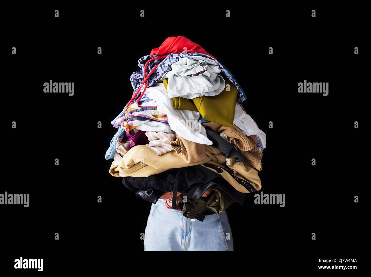 a woman holds a lot of crumpled clothes in her hands, black background, copy-paste Stock Photo