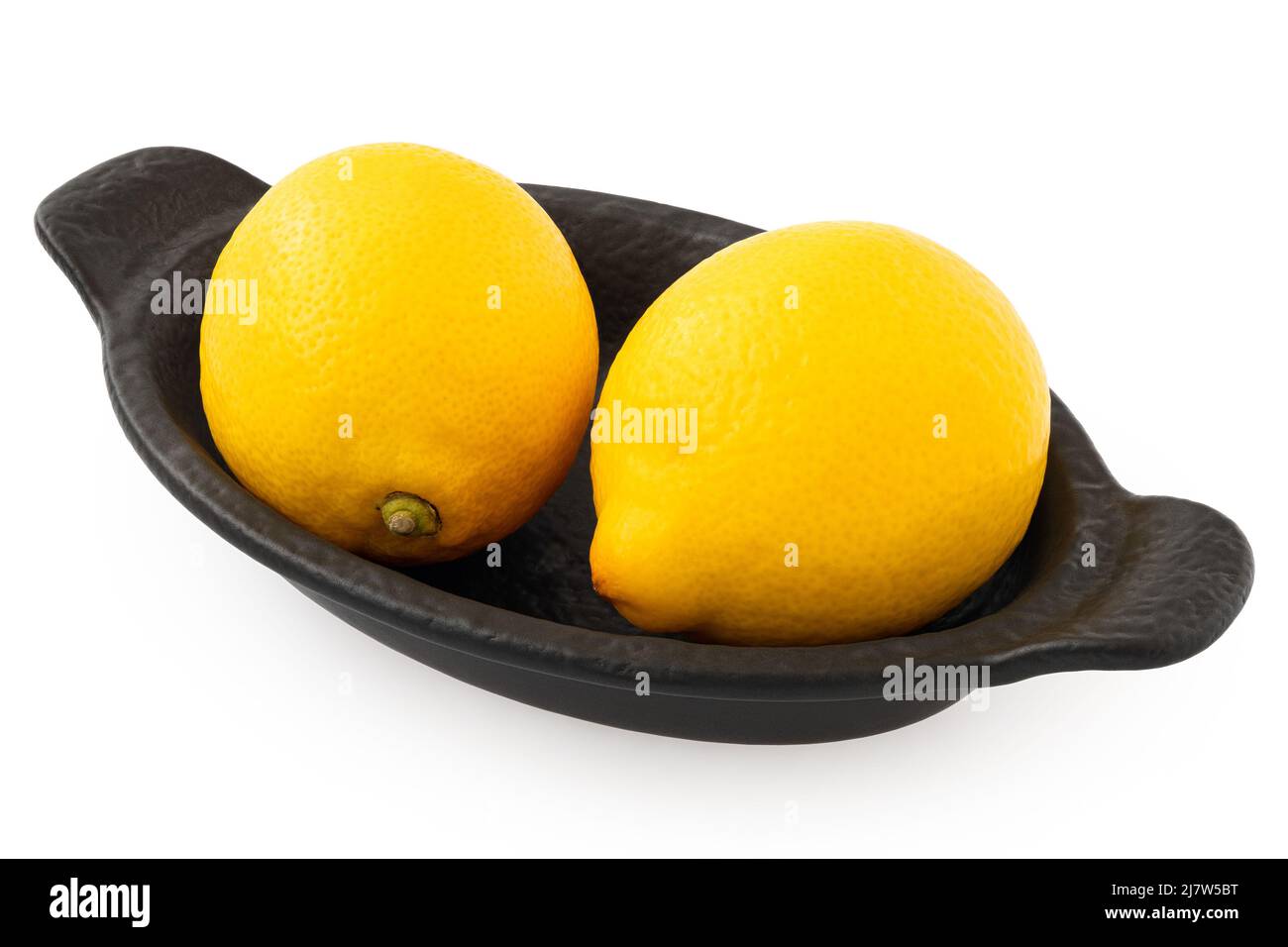 Two whole fresh lemons on black ceramic dish isolated on white. Stock Photo