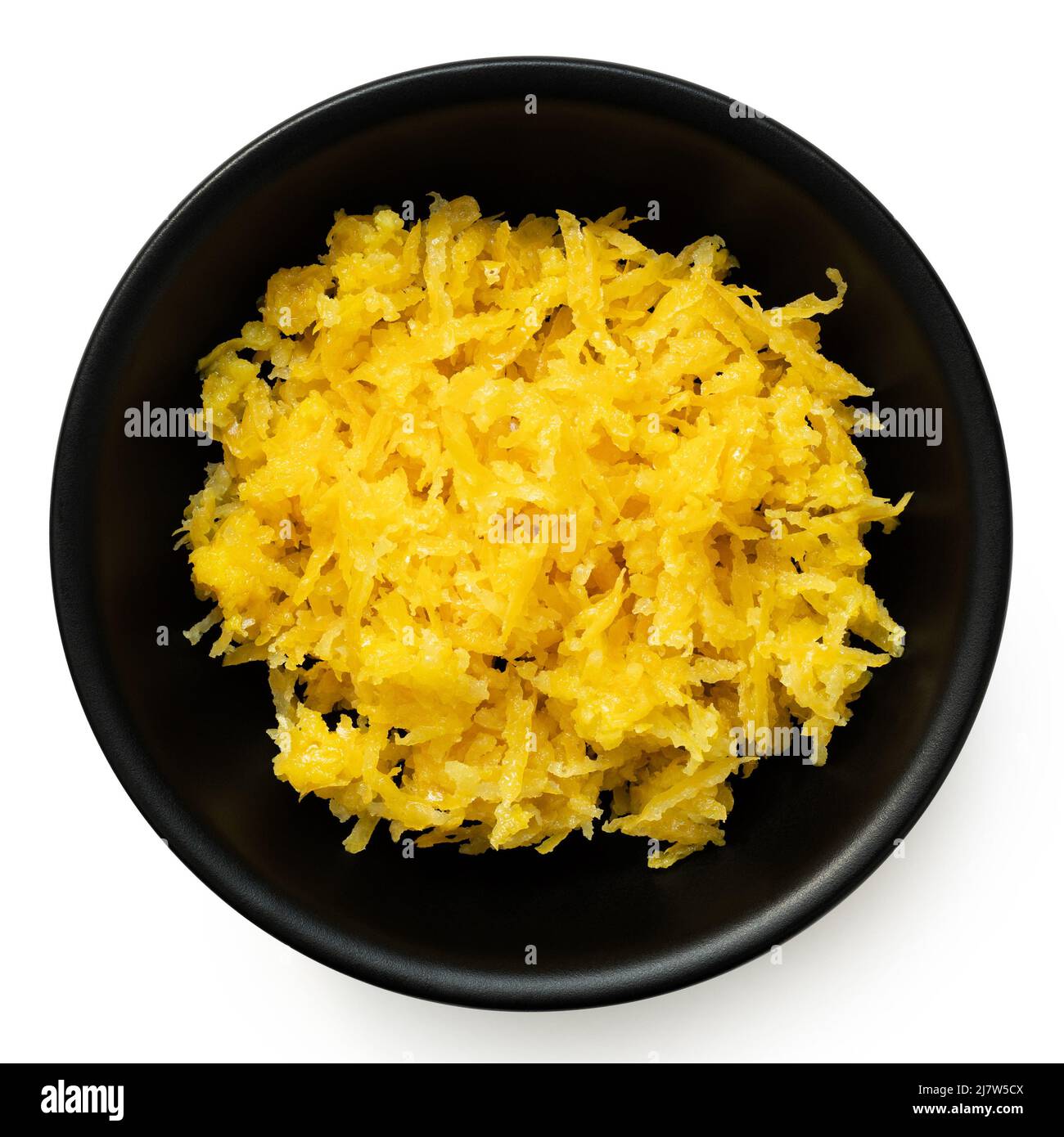 Freshly grated lemon zest in a black ceramic bowl isolated on white. Top view. Stock Photo