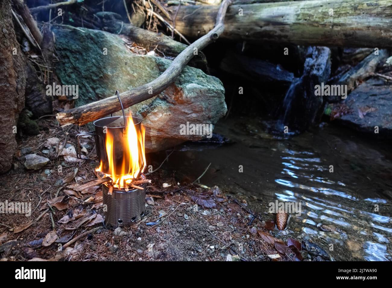 bushcrafting with a pot and boiling water over a fire by a creek Stock