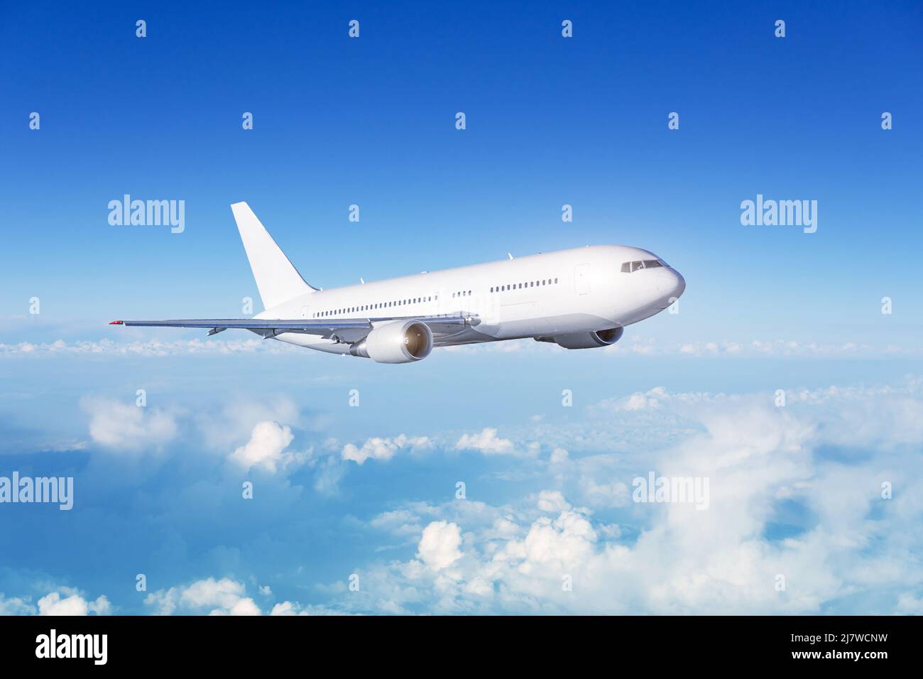 White passenger wide body plane. Aircraft is flying in blue cloudy sky Stock Photo