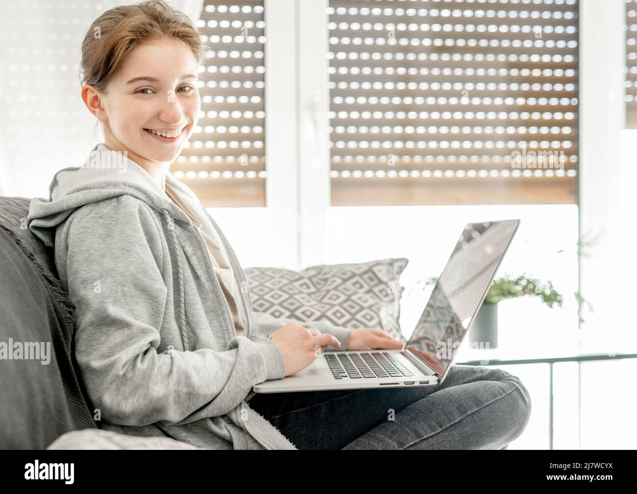 Happy little girl looking at computer screen sitting at desk in ...