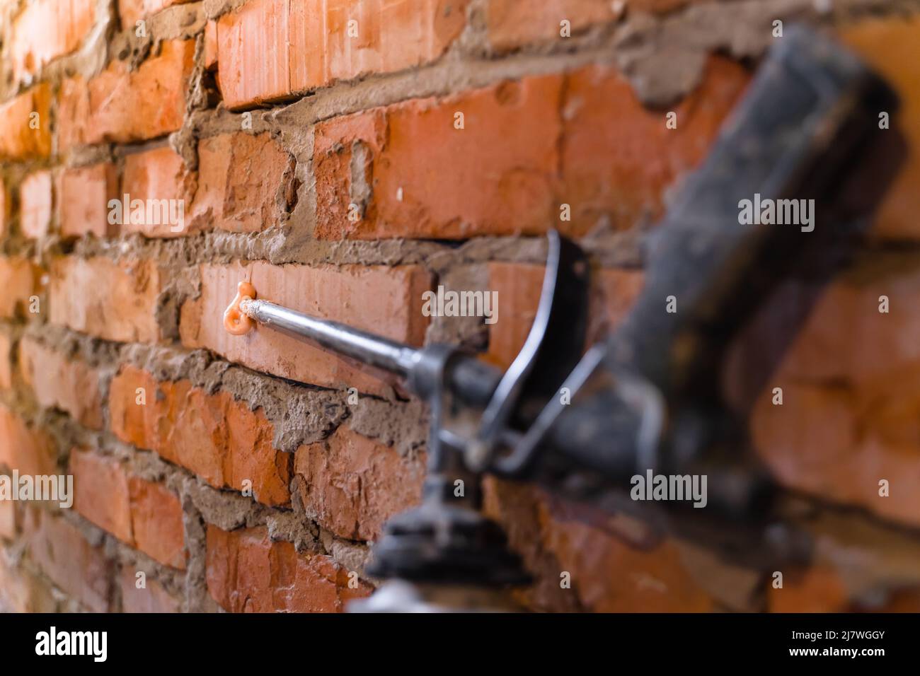 Foam gun with leaking foam on the nose. Mounting foam on brick wall