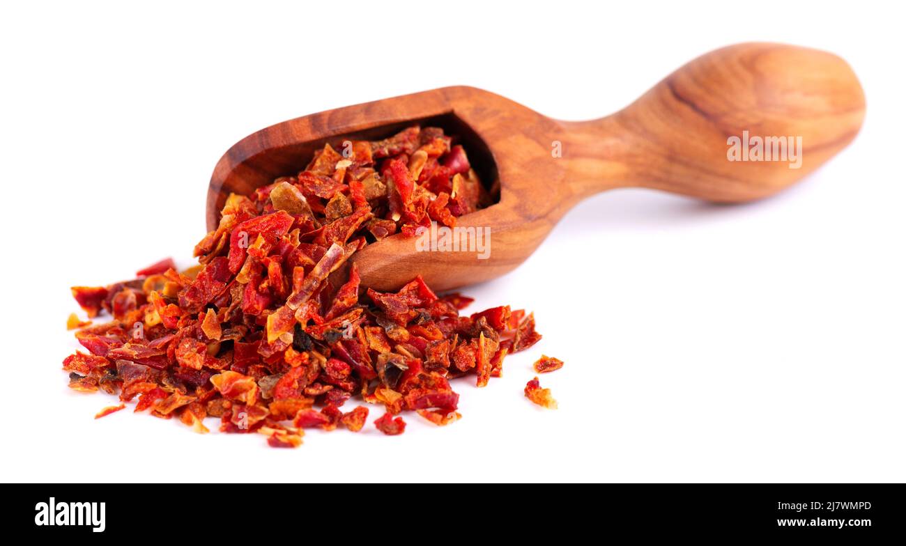 Dried red paprika flakes in olive scoop, isolated on white background